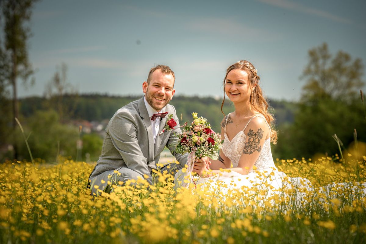 Brautpaar zwischen gelben Blumen auf einer Wiese